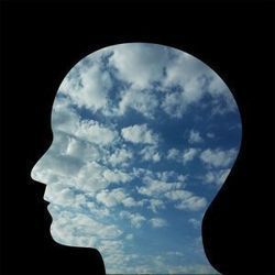 silhouette of a head superimposed over a photo of clouds